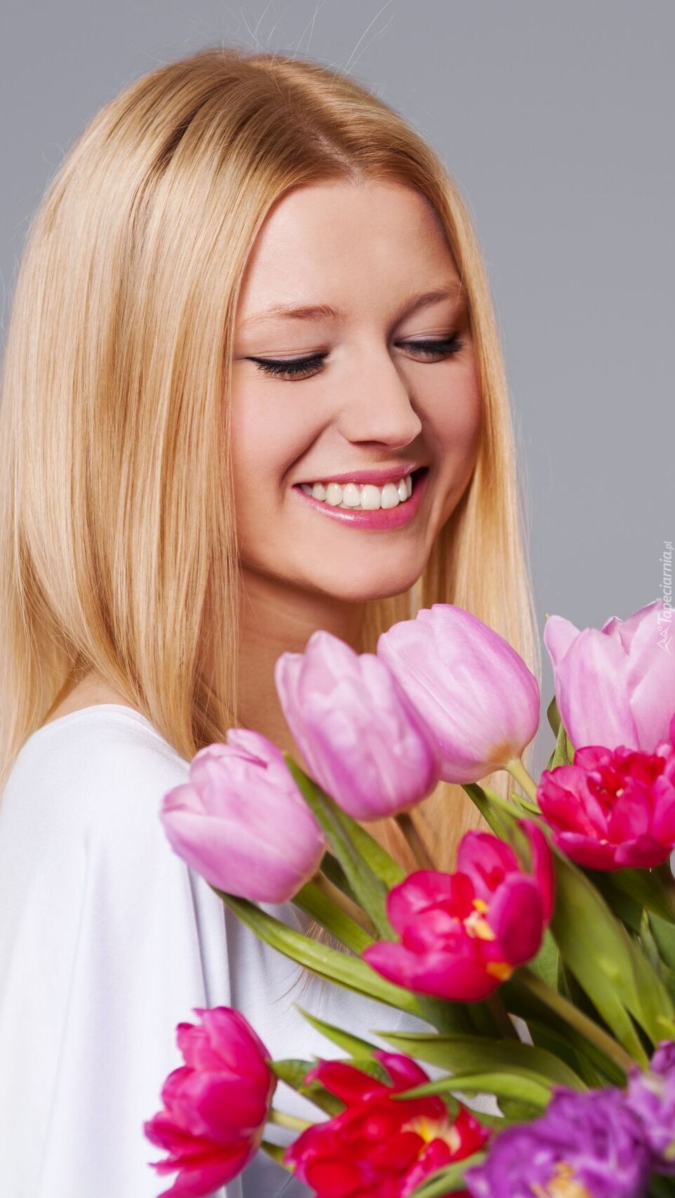 Uśmiechnięta blondynka z bukietem tulipanów