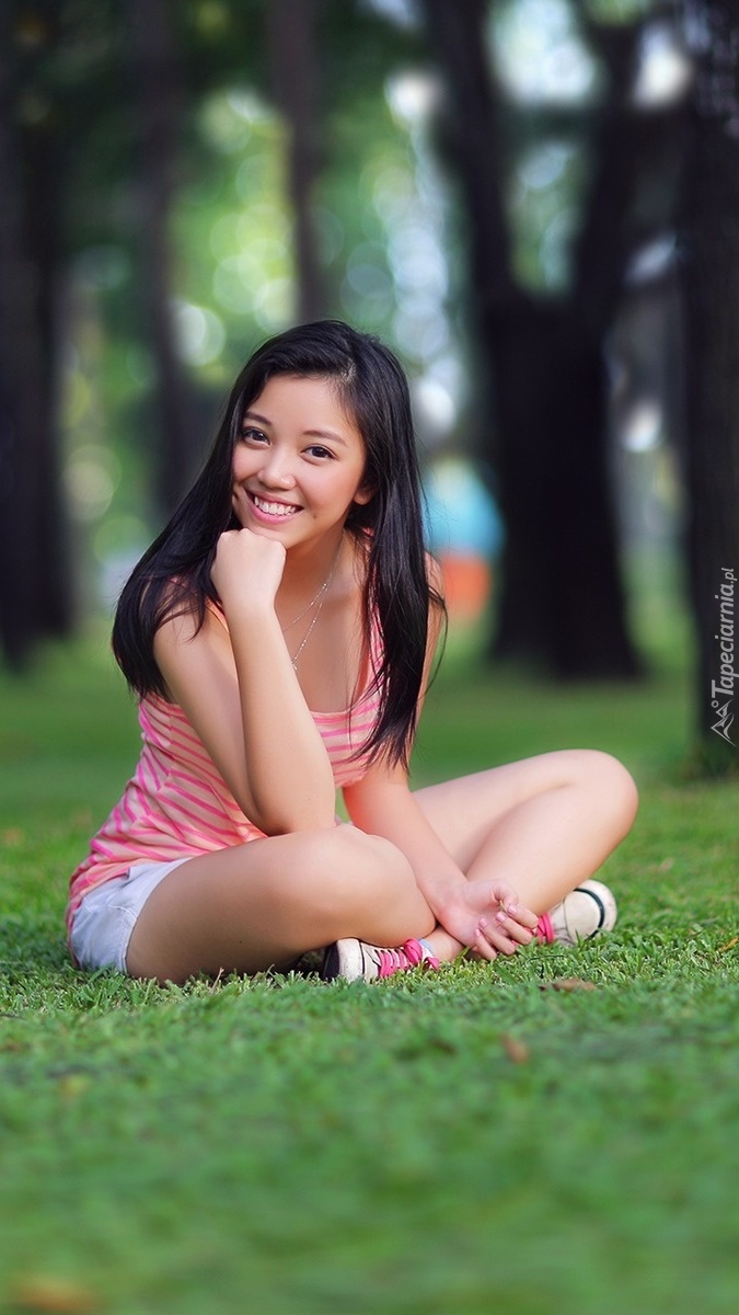 Uśmiechnięta brunetka w parku na trawie