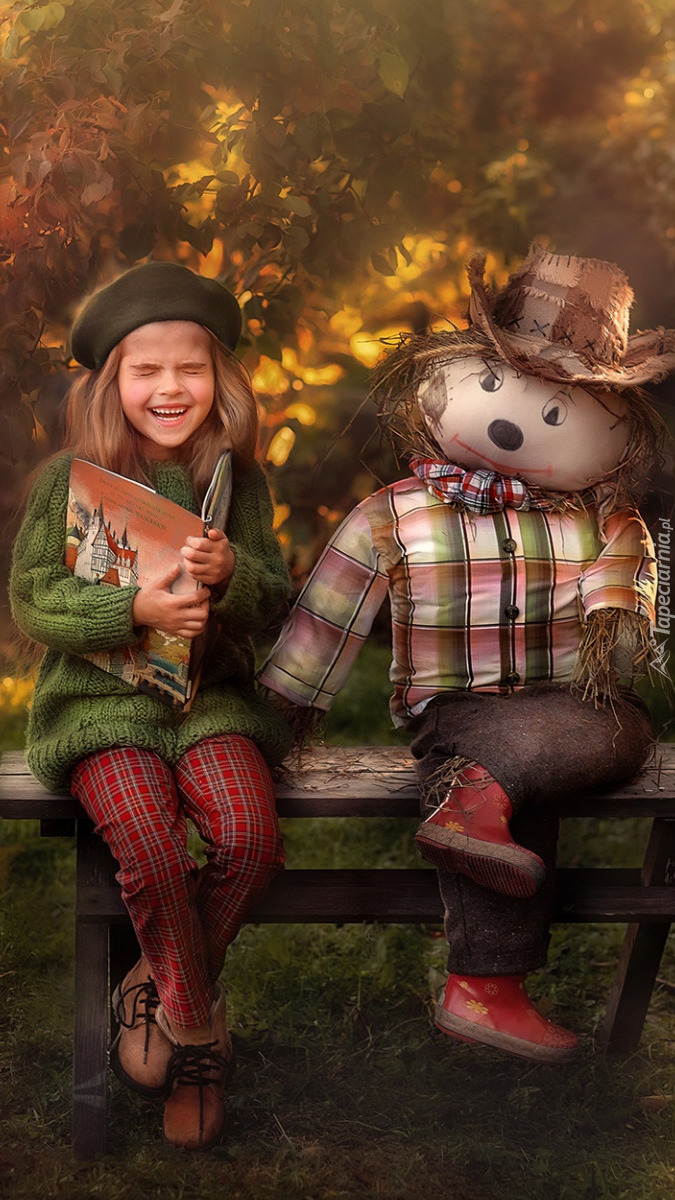Uśmiechnięta dziewczynka i szmaciana lalka na ławce