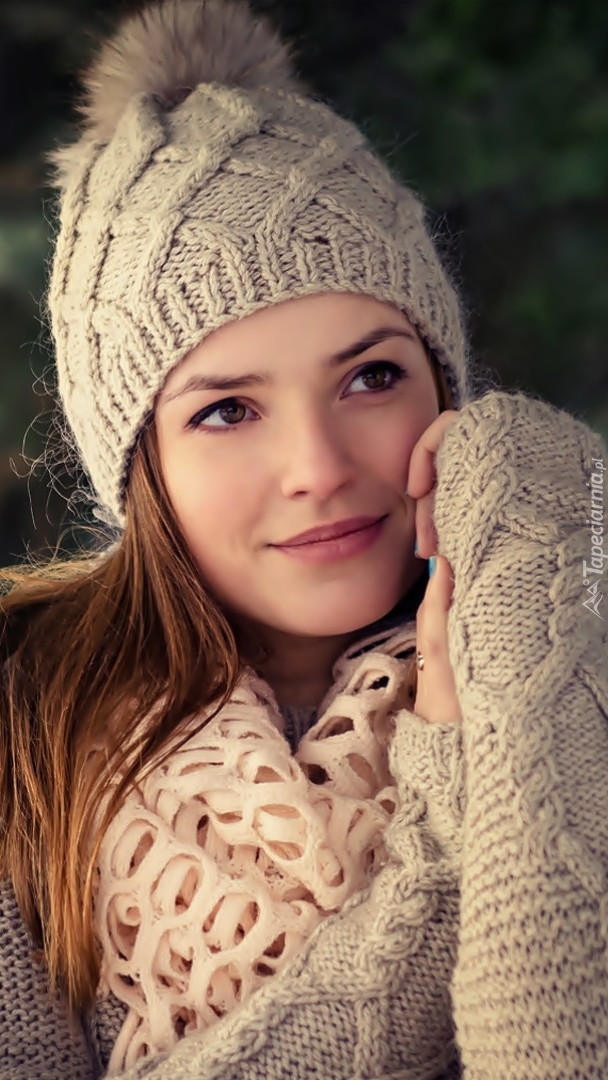 Uśmiechnięta kobieta w czapce i swetrze