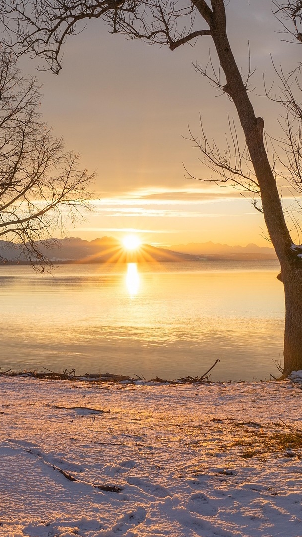 Widok na zachód słońca nad jeziorem i górami zimową porą