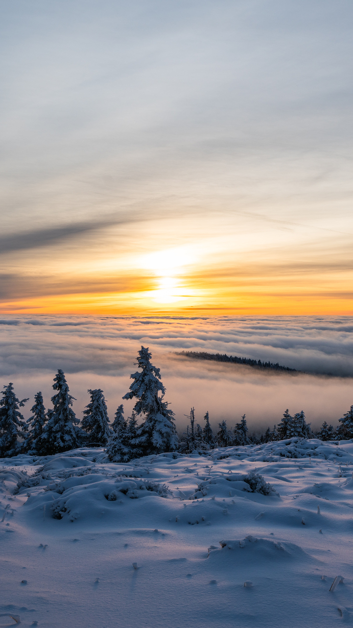 Widok z ośnieżonego pola na zachód słońca nad chmurami