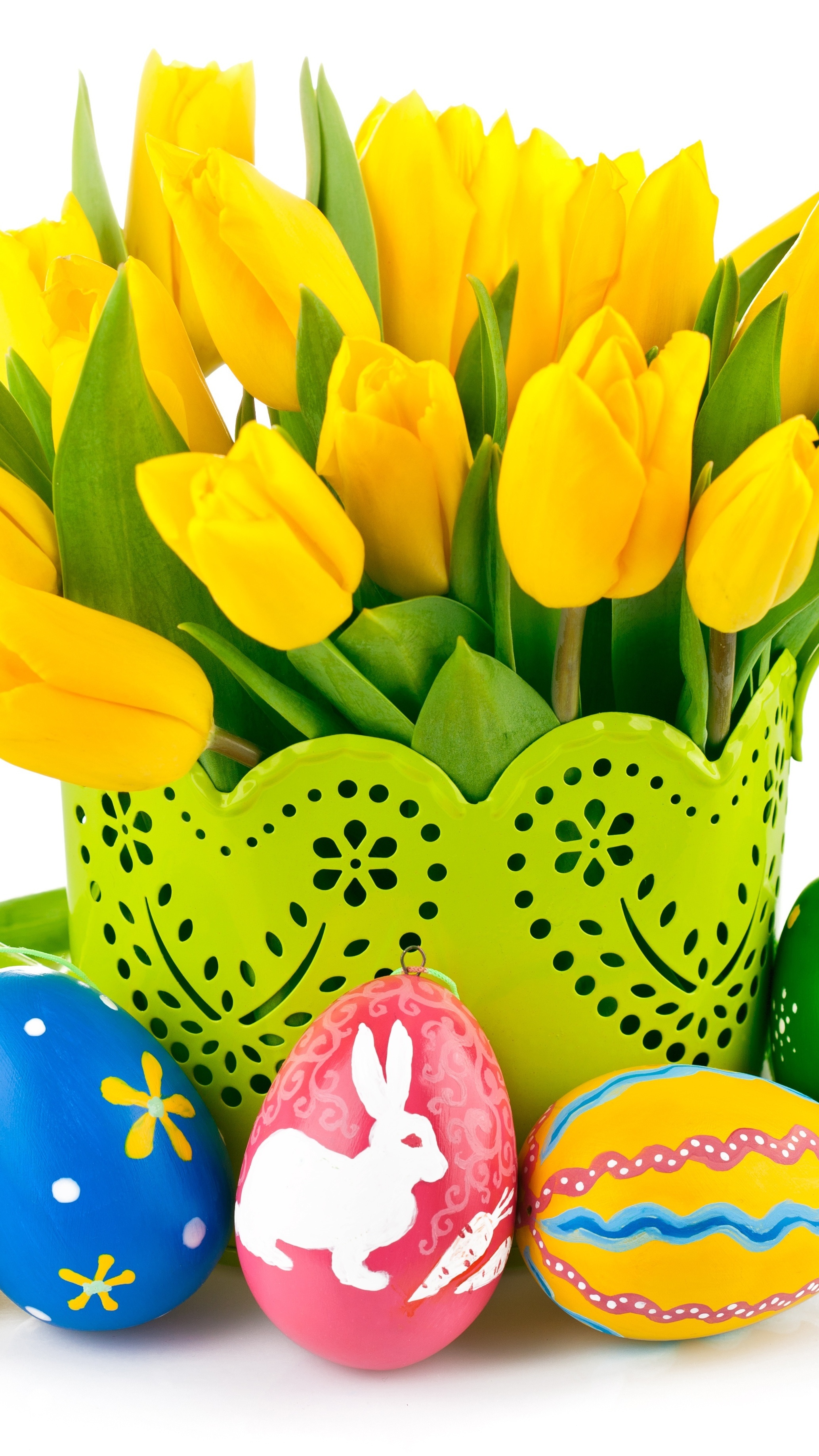 Wielkanocne pisanki obok żółtych tulipanów