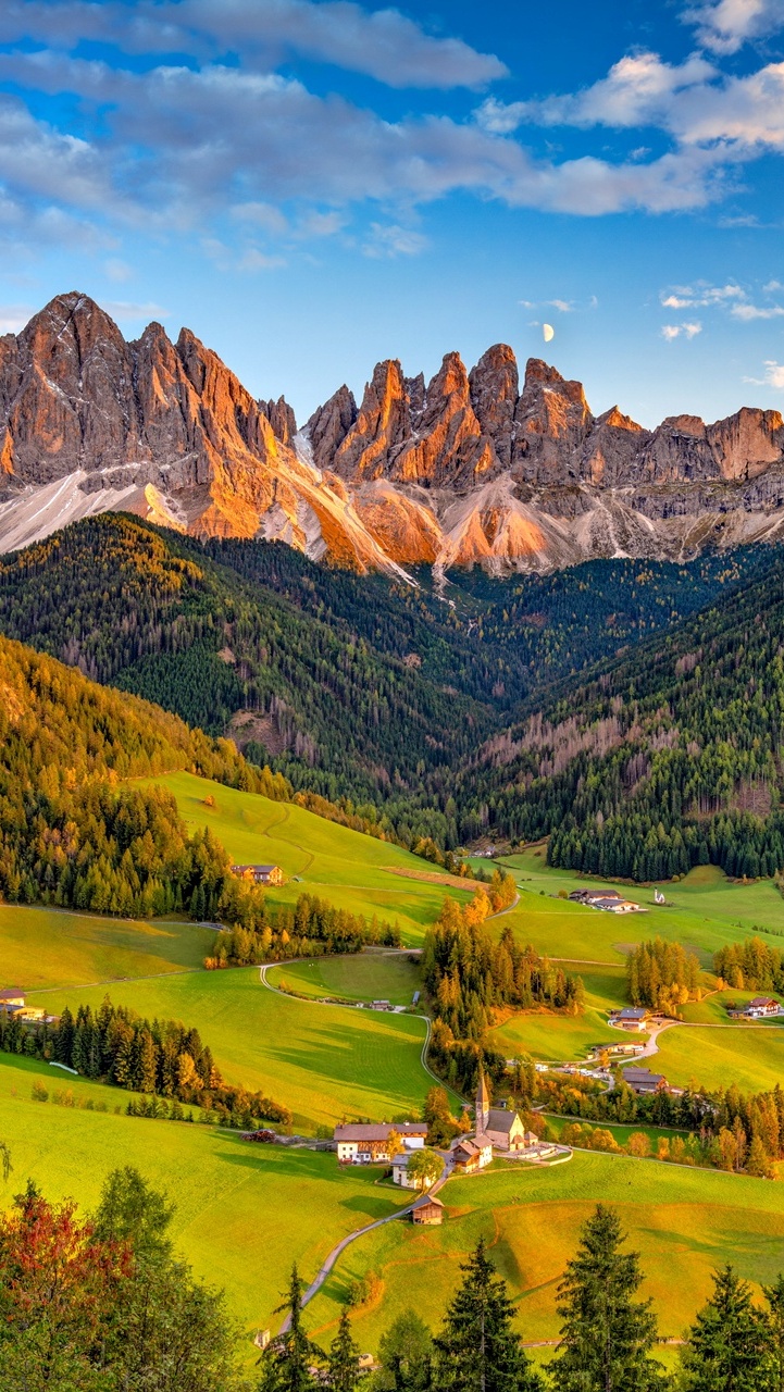 Wieś Santa Maddalena w dolinie Val di Funes i Dolomity w oddali