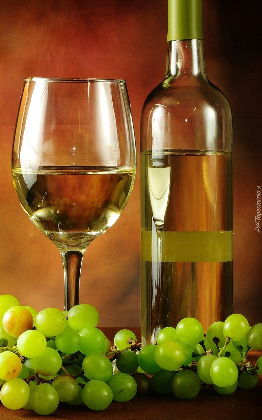 Wino w kieliszku obok butelki i winogron