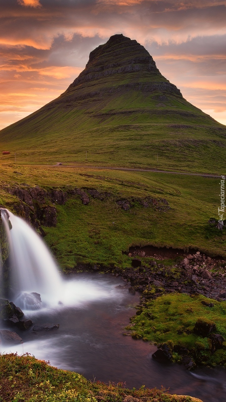 Wodospad Kirkjufellsfoss u podnóża góry Kirkjufell w promieniach słońca