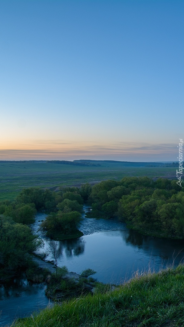 Wzgórza nad rzeką otoczone lasami i łąkami