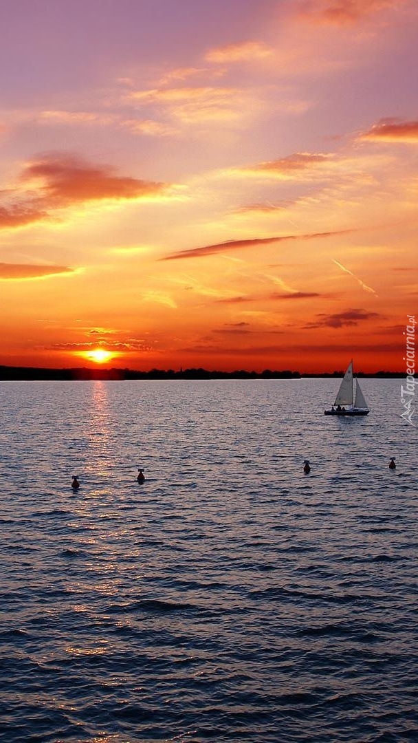 Żaglówka na jeziorze o zachodzie słońca