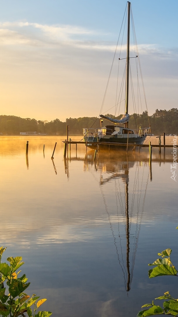 Żaglówka przy pomoście na jeziorze Schwielochsee o wschodzie słońca