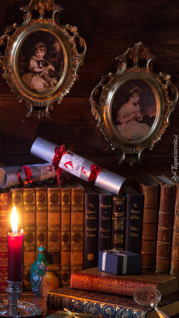 Zapalona świeca obok książek i prezentu