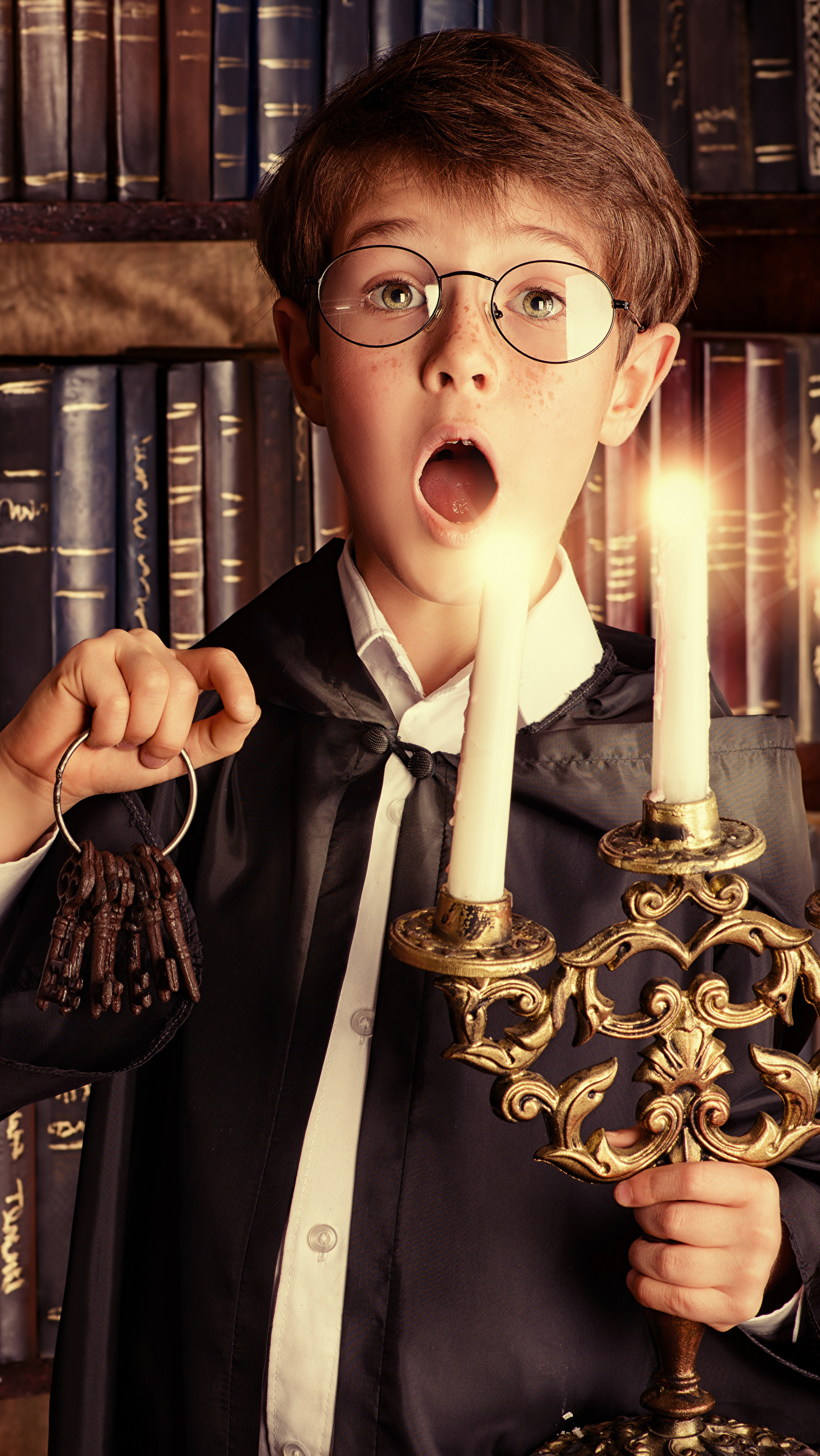 Zdziwiony chłopiec w okularach ze świecznikiem i kluczami