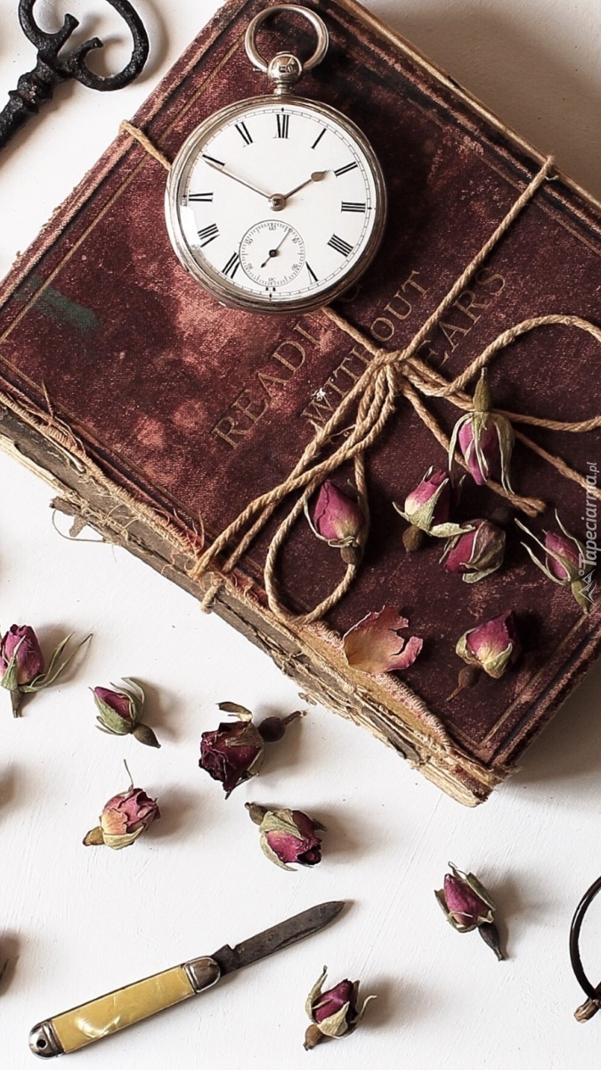 Zegarek i zasuszone różyczki na starej książce