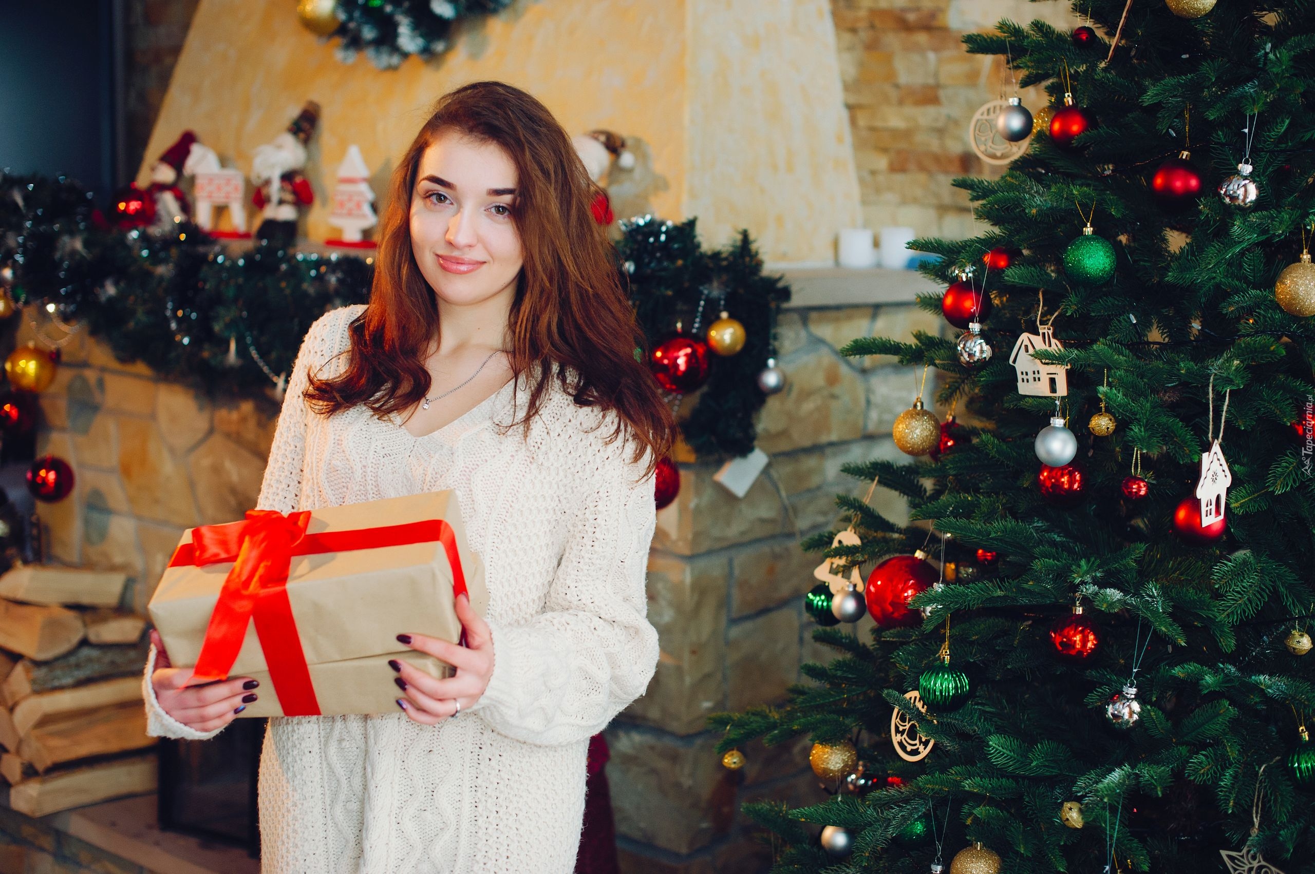 Dziewczyna z prezentem obok świątecznej choinki
