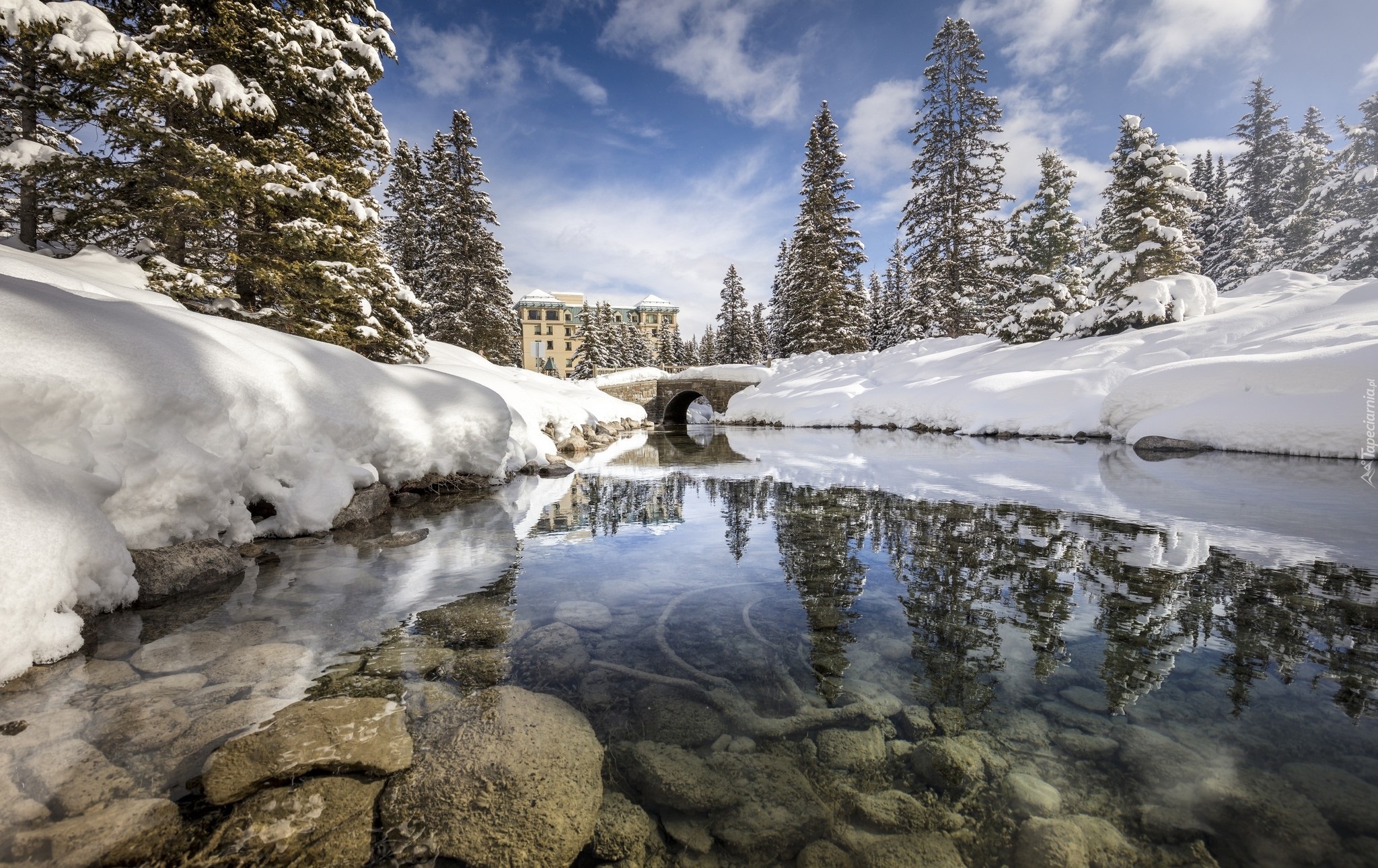 Kanada, Prowincja Alberta, Park Narowy Banff, Miejscowość Lake Louise, Jezioro Louise, Hotel Chateau Lake Louise, Zima, Rzeka, Most, Kamienie, Ośnieżone, Świerki