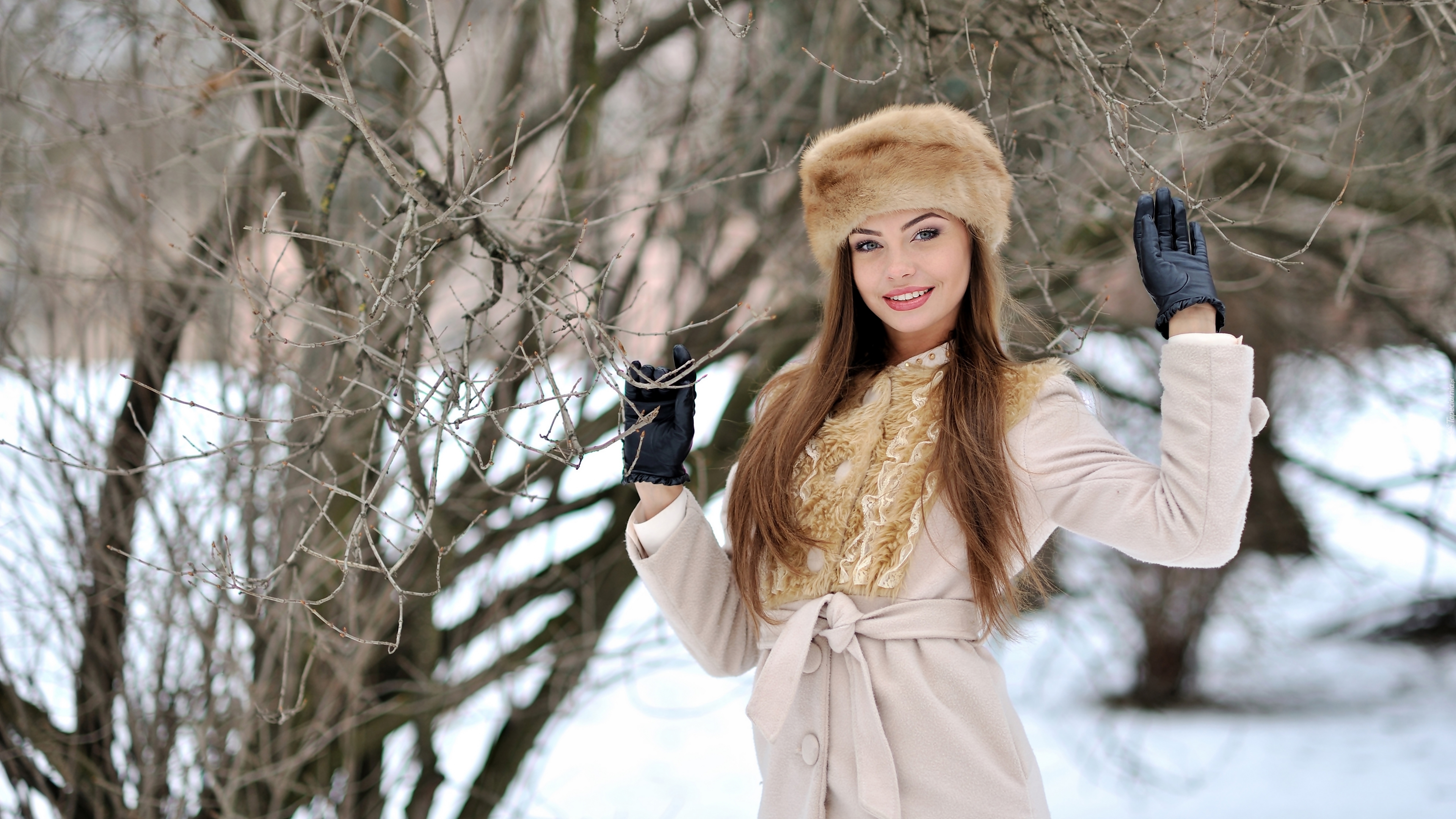 Uśmiechnięta dziewczyna w czapce przy drzewie
