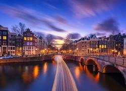 Amsterdamski kanał z mostem i widokiem na oświetlone domy