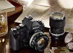 Aparat fotograficzny marki Nikon obok rozłożonej mapy i zegarka