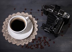 Aparat fotograficzny obok filiżanki z kawą