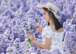 Azjatka w kapeluszu na polu kwiatów