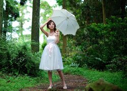 Azjatka z parasolką w lesie