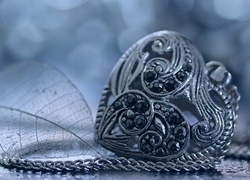 Ażurowy listek obok naszyjnika z zawieszką w kształcie serca