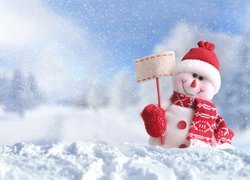 Bałwanek w czapeczce i szaliku na śniegu