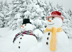 Bałwany w kolorowych szalikach i kapeluszach stoją dumnie na śniegu