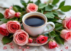 Biała filiżanka z kawą na talerzyku w otoczeniu różowych róż