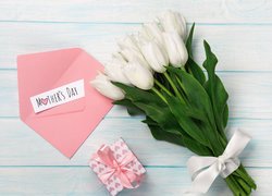 Białe tulipany obok koperty i prezentu dla mamy