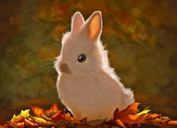 Biały króliczek siedzący na jesiennych liściach