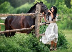 Brunetka w białej sukience przy koniu