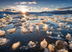 Bryły lodu na jeziorze Jökulsárlón w Islandii o zachodzie słońca