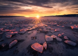 Bryły lodu na zamarzniętym jeziorze w blasku wschodzącego słońca