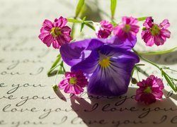 Bukiecik kwiatów położony na kartce z miłosnym wyznaniem