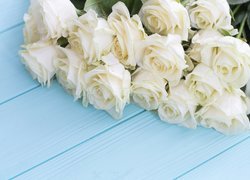 Bukiet białych róż położony na deskach
