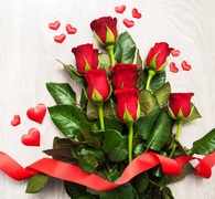 Bukiet czerwonych róż ozdobiony wstążką i serduszkami