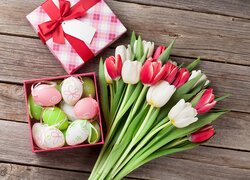 Bukiet kolorowych tulipanów obok pudełka z pisankami
