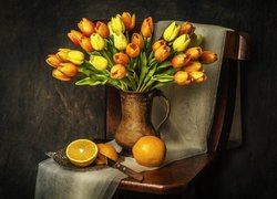 Bukiet kolorowych tulipanów w dzbanku obok pomarańczy na krześle