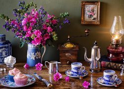 Bukiet kwiatów obok lampy i serwisu kawowego