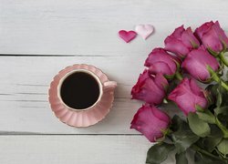 Bukiet róż obok filiżanki z kawą i serduszek