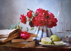 Bukiet róż obok książek, gruszek i kieliszka z wodą przy butelce