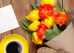 Bukiet tulipanów w papierze obok filiżanki kawy