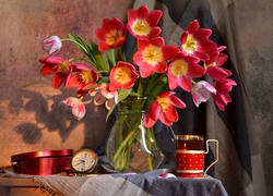 Bukiet tulipanów w wazonie obok szklanki z herbatą