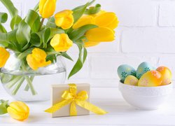 Bukiet żółtych tulipanów obok prezentu i pisanek