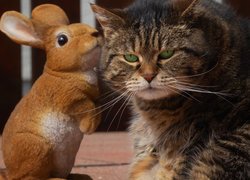 Bury zielonooki kot obok figurki zajączka