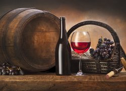 Butelka i kieliszek z winem obok koszyka z winogronami i beczki