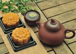 Ceramiczny czajnik z filiżanką obok ciastek