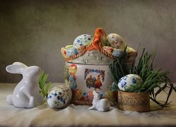 Ceramiczny koszyczek z pisankami obok figurek zajączków