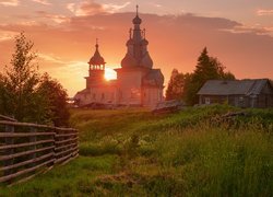 Cerkiew i domy na łące o wschodzie słońca