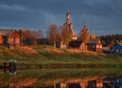 Cerkiew i domy we wsi Kimzha w blasku zachodzącego słońca